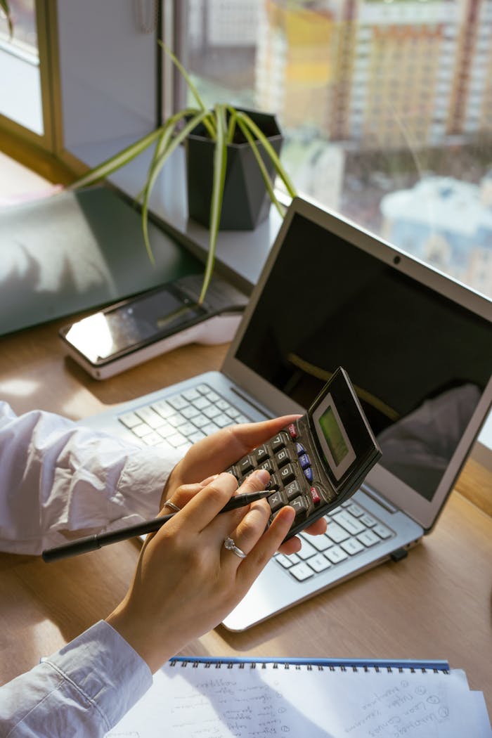 Person Using a Calculator and a Laptop